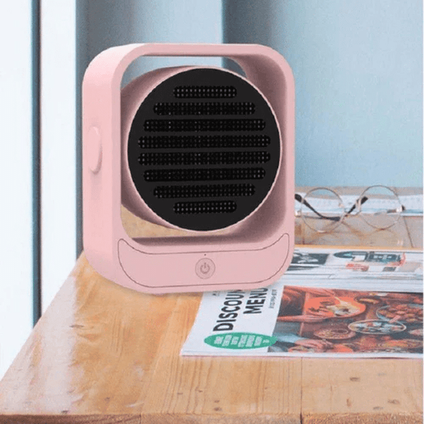 Portable Energy Efficient Desktop Heater on a wooden desk next to glasses and magazines, providing quick warmth.
