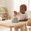 Child joyfully playing with Press and Spin Carousel Toy for Kids on a table in a bright room.