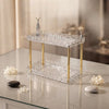 Double-Layer Water Ripple Beauty Organizer Shelf elegantly displayed on a vanity with decorative stones and flowers.
