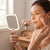 Woman using a Portable Square LED Makeup Mirror to apply blush while getting ready.