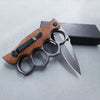 Tactical Trench Folding Knife with wooden handle and knuckle guard next to a black box.