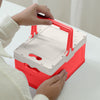 Person holding a Foldable Plastic Camping Storage Box with a red base and white lid for easy transport.