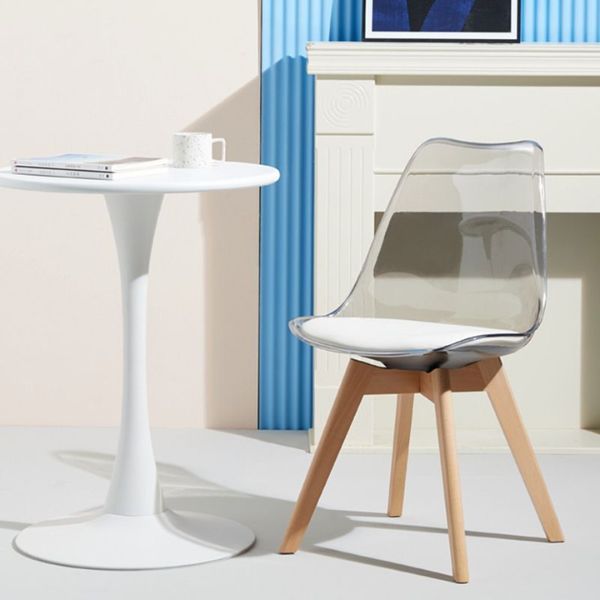 Scandinavian Transparent Elk Dining Chair next to a white table in a modern interior setting.