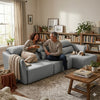 Couple enjoying drinks on the Bina Cinematic Couch in a cozy living room setting with a dog.