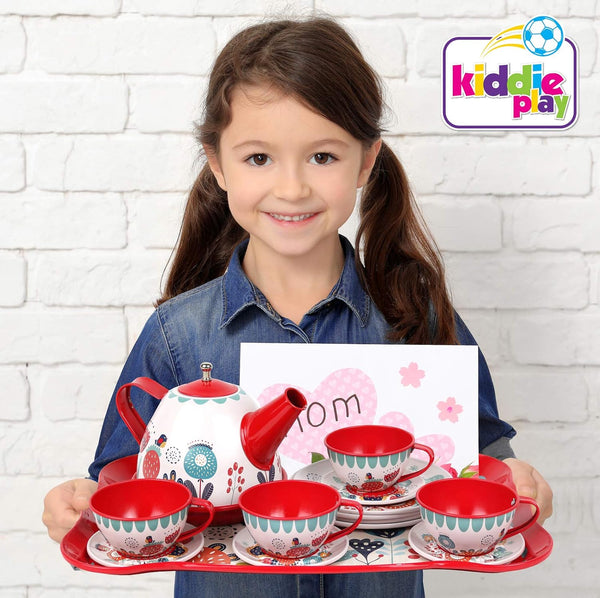 A child happily holds the Floral 15-Piece Kids Tin Tea Set with Carrying Case, featuring a teapot and cups.