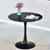 Round Dining Table with black finish and stylish design, featuring a vase of flowers and a cup on top.
