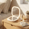 Portable Rechargeable Seashell LED Mirror on a wooden table with skincare products and a decorative plant.