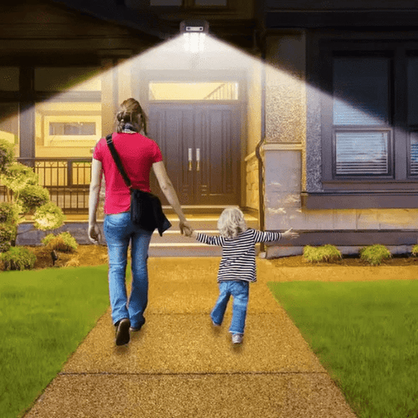 A woman and a child walking on a lit pathway illuminated by a Remote-Control LED Outdoor Light.