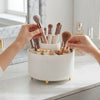 360-Degree Rotating Desktop Storage Bucket with makeup brushes and cosmetic products organized elegantly on a vanity.
