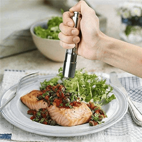 Chef Master Adjustable Salt & Pepper Grinder in use to season a salmon dish with herbs and greens.
