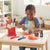 Kitchen Helper Happy Little Chef Pretend Play set with a young girl using toy knives and food for imaginative kitchen play.
