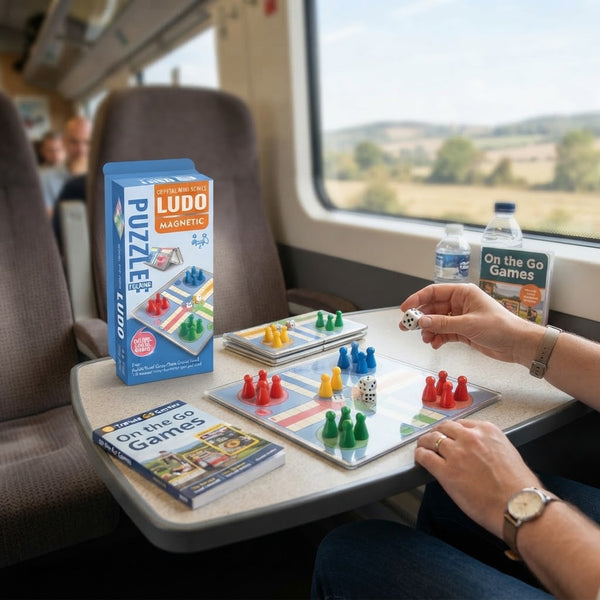 Mini Magnetic Ludo Board Game being played on a train table with pieces and dice.