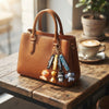 3D Animal Silicone Keychain hanging from a stylish brown handbag on a wooden table near a coffee cup.