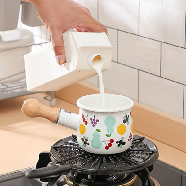 Pouring milk into a Small Enamel Milk and Butter Warming Pot on a stove for easy heating.