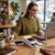 Woman using 58000mAh Waterproof Power Bank with 22.5W Fast Charging at café while working on laptop.