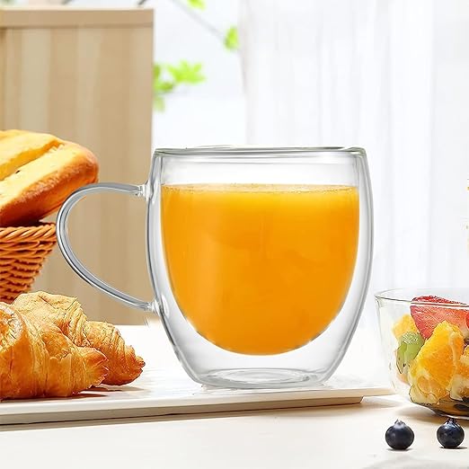 Heat Resistant Transparent Glass Coffee Mug filled with orange juice on a breakfast table with pastries.