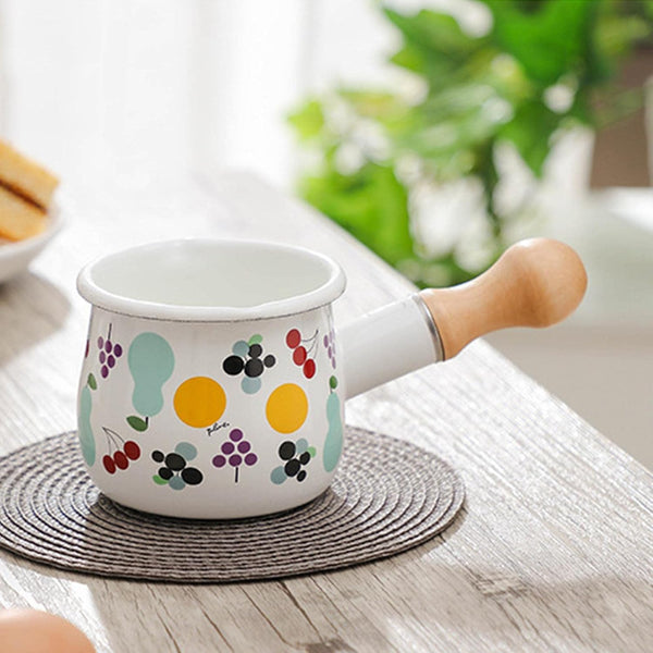 Small Enamel Milk and Butter Warming Pot with colorful fruit designs on a kitchen table.