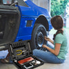 A person using the 93 Piece Tire Repair Tool Set to fix a tire on a blue car in a garage.