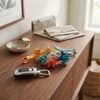 Colorful 3D Cartoon Dinosaur Keychain designs displayed on a wooden table with car keys and a bowl.