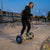 A person riding an Electric Self-Balancing Hoverboard at a skate park with graffiti background during sunset.