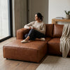 A woman enjoying a cozy moment on a Genuine Leather U-Shaped Sectional Couch, holding a mug and relaxing.