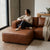 A woman enjoying a cozy moment on a Genuine Leather U-Shaped Sectional Couch, holding a mug and relaxing.