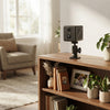 2MP 1080P Security Camera positioned on a shelf next to plants and framed photos in a bright indoor setting.