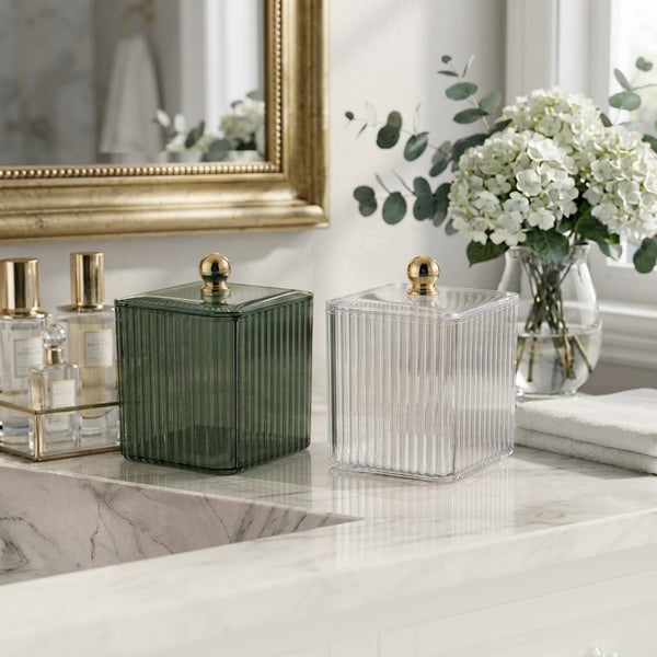 Clear Ribbed Acrylic Storage Box with Dust-Proof Lid displayed on a bathroom counter alongside a green box and flowers.