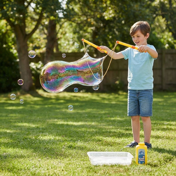 Child using the Double Bubble Giant Bubble Wand to create a giant bubble in a garden.