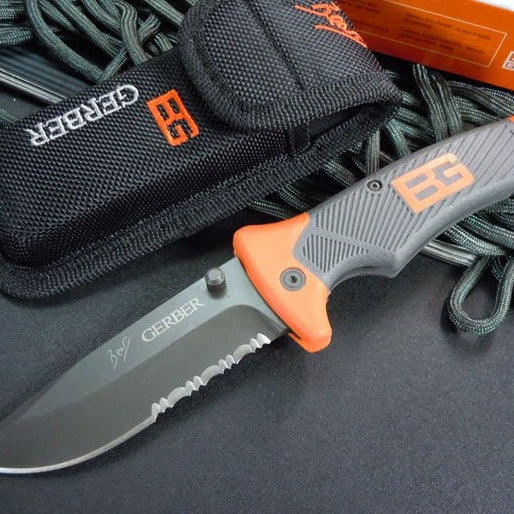 Bear Grylls Gerber Survival Knife with serrated edge and durable grip on a black surface.