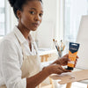 Acrylic Paint 75ml - Orange Yellow in hand, showcasing vibrant color for artwork in a studio setting.