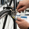Hands using a wrench on a bicycle wheel, demonstrating the Bicycle Tyre Repair Kit in action.