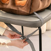 Person securing straps of a Baby Safety Support Seat on a chair for enhanced safety during bath time or feeding.