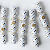 Festive Christmas Popper Crackers arranged neatly in a row, featuring elegant white and gold striped designs.