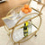 2 Tier Mobile Serving Trolley with glassware, bottles, and oranges on mirrored shelves.