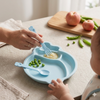 Divided Plate & Cup Set with Utensils shown with a baby eating, featuring a divided plate, utensils, and vegetables.