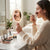 Woman using LED Hand Mirror with Integrated Lighting for makeup application in a bright room.