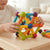Child building with the Rainbow Magnetic Construction Sticks & Balls Set on a wooden table, creating colorful geometric shapes.