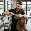 A hairstylist using Portable Stainless Steel Hairdressing Thinning Scissors on a client's hair in a salon.