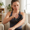 Woman using Multi-Roller Muscle Massage Tool on her arm while seated on a comfortable chair.