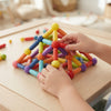 Child building with the Colourful Sticks & Balls Construction Set, creating a colorful pyramid structure.