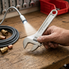 Professional Adjustable Torque Wrench being used on wood surface with pipes and lighting in background.
