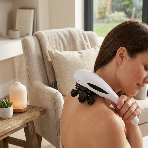 A woman using the 5-Head Handheld Massager on her shoulder while relaxing at home.