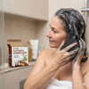 Woman using Tuber Fleeceflower Root Extract Shampoo Soap in the shower for healthy hair care.
