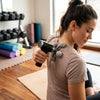 Woman using the 5-Ball Handheld Massager on her back for targeted relief in a fitness setting.