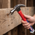 Using a Polished 16oz Claw Hammer with Shock-Reduction Grip to drive a nail into wooden planks.