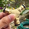 Heavy Duty Brass 3-Way Garden Hose Splitter held by a hand, showcasing its sturdy design and functionality.