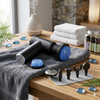 Professional Deep Tissue Muscle Massage Gun with attachments on a towel in a spa-like setting