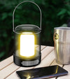 Portable USB Camping & Tent Lamp illuminating a table next to a phone and a metal cup.