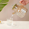 Elegant Large Capacity All-Glass Tea Set pouring tea into a glass cup with a golden handle and attractive design.